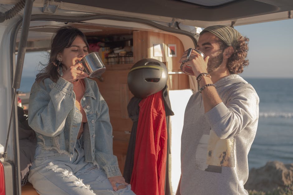 Casal a relaxar com vista para o mar, dentro de uma van.