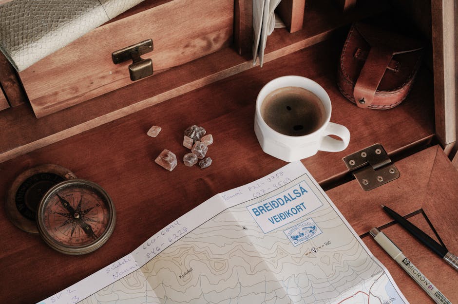 Mesa com mapa, bússola e café, vista de cima.
