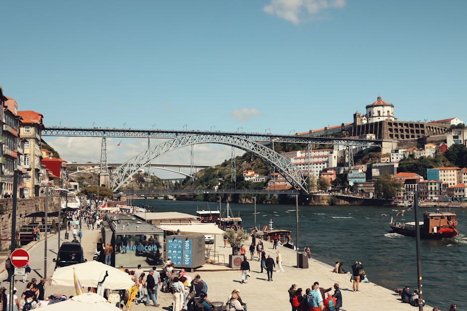 Bustling scene of the Dom Luís I Bridge over the Douro River in Porto with tourists and cityscape.
