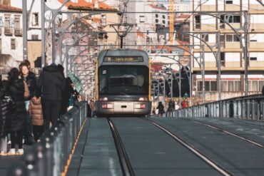 A metro tram traveling on the Ponte Luís I Bridge in Porto, Portugal, surrounded  urban architecture.