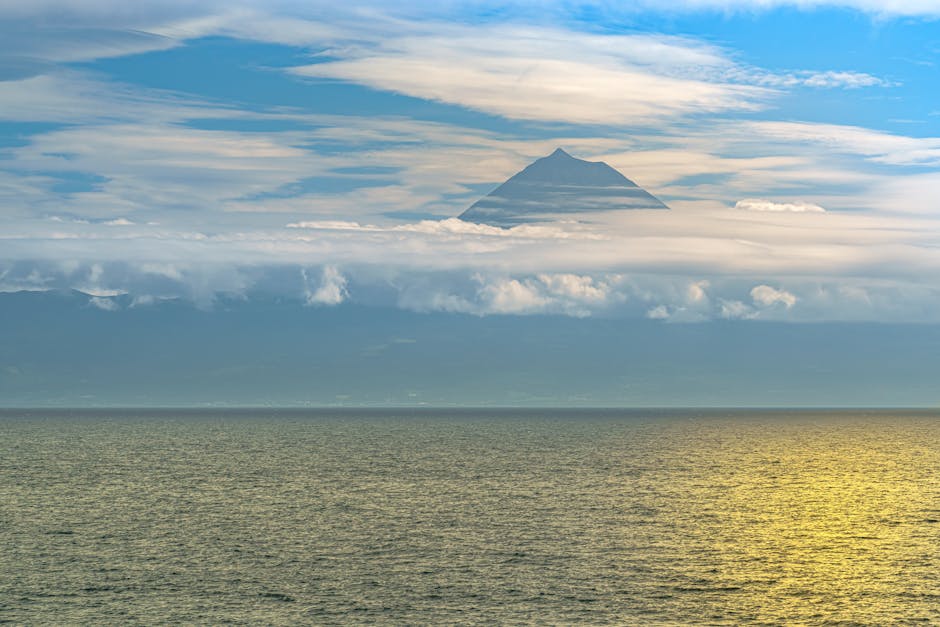 Serene seascape of the Azores with Mount Pico silhouetted against the sky.