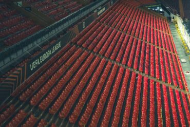 Filas de assentos vermelhos vazios num estádio da Liga Europa da UEFA, capturadas de cima.