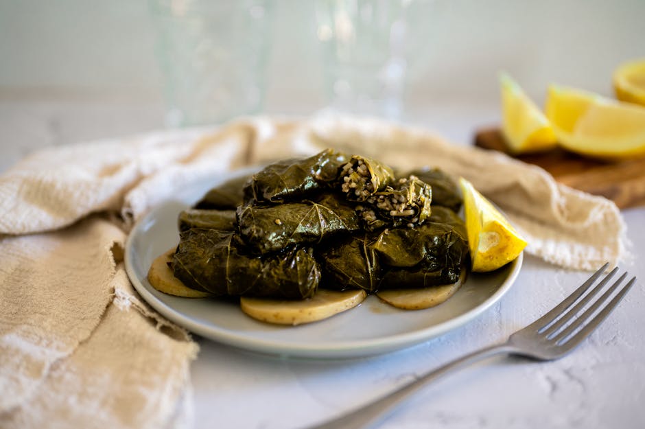 Close-up de folhas de uva recheadas num prato com rodelas de limão, perfeitas para uma refeição mediterrânica.