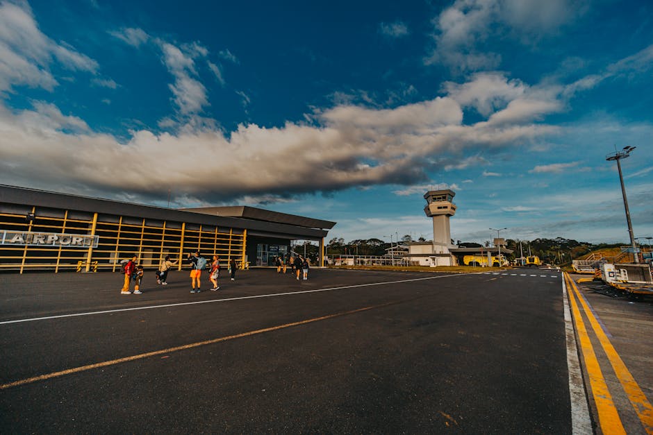 Um pequeno terminal de aeroporto com pessoas a caminhar na pista sob um céu azul.