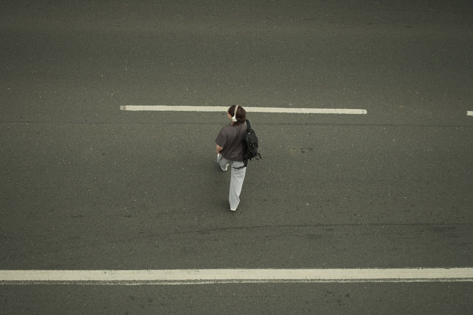 Uma vista aérea que capta uma pessoa solitária a caminhar numa estrada da cidade, enfatizando a solidão e a viagem.