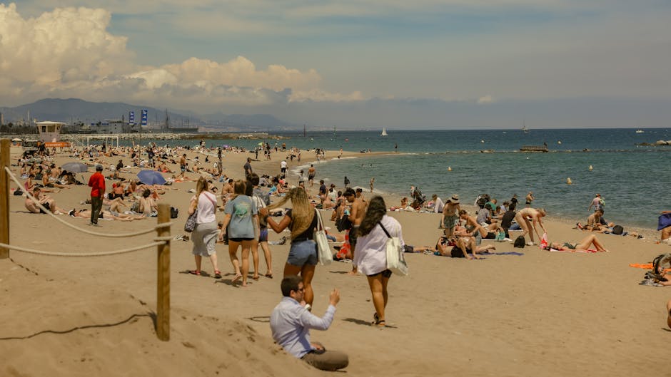Cena de praia movimentada em Barcelona com pessoas a desfrutar de um dia de verão soalheiro.