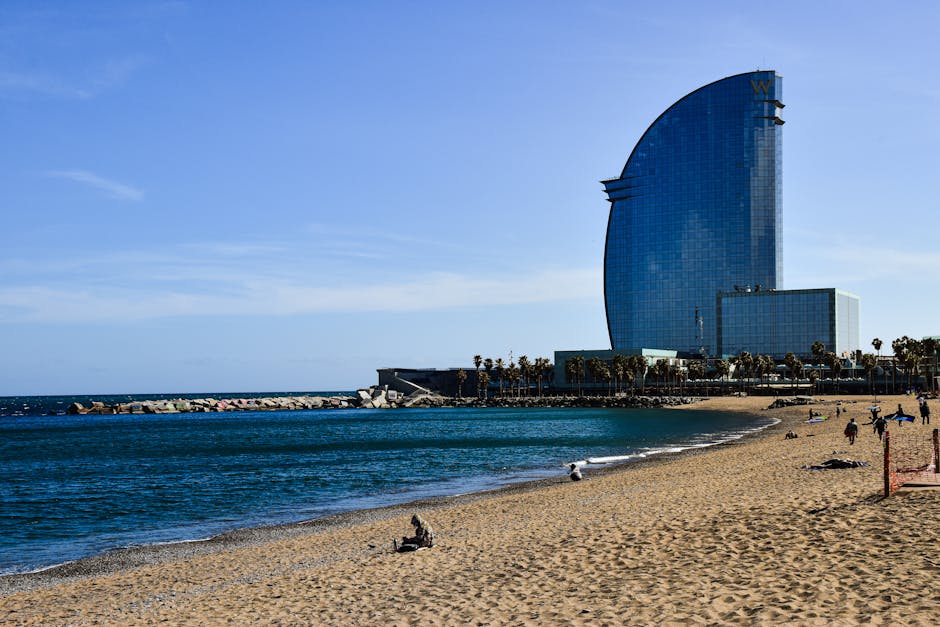 Vista da praia de Barcelona com o icónico Hotel W e céu azul límpido.