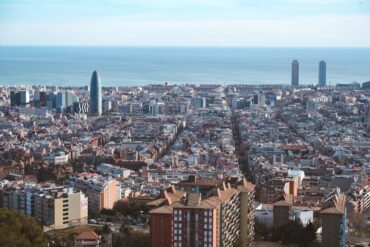 Vista aérea panorâmica da paisagem urbana de Barcelona, mostrando o Mar Mediterrâneo e a arquitetura icónica.