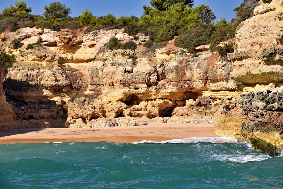 Belas falésias do Algarve com oceano turquesa e praia de areia no Distrito de Faro, Portugal.