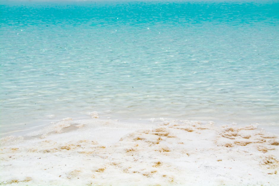 Cenário de praia sereno com água azul-turquesa cristalina e areia branca imaculada.