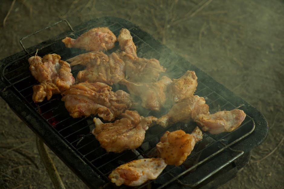 Asas de frango suculentas a chiar numa grelha a carvão, perfeitas para churrascos ao ar livre.
