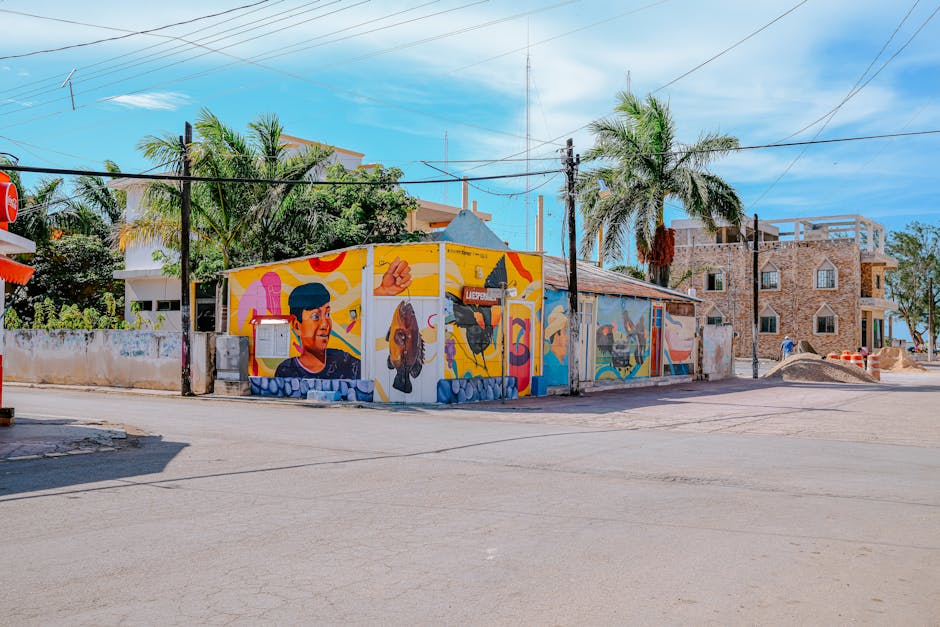 Mural vibrante numa parede de edifício urbano com palmeiras num dia soalheiro.