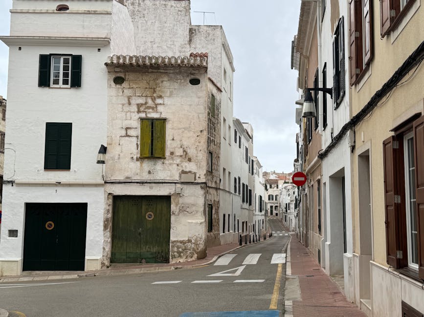 Uma rua tranquila e pitoresca ladeada por edifícios antigos de pedra numa pequena vila espanhola.
