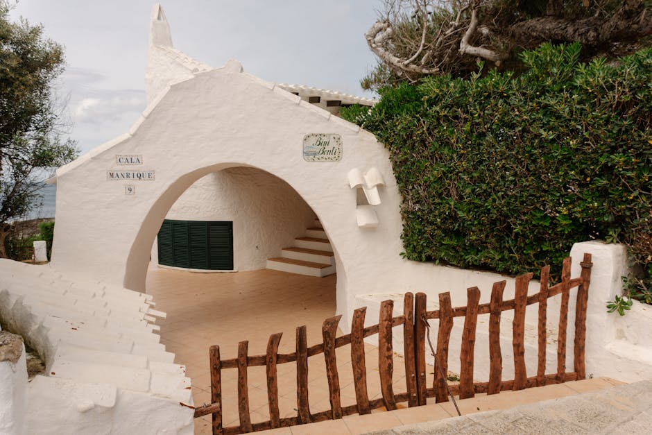 Edifício idílico caiado de branco com arcos em Ciutadella de Menorca, a exibir o design tradicional das Baleares.