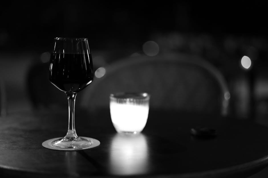 Um copo de vinho e uma vela numa mesa num café parisiense, à noite.