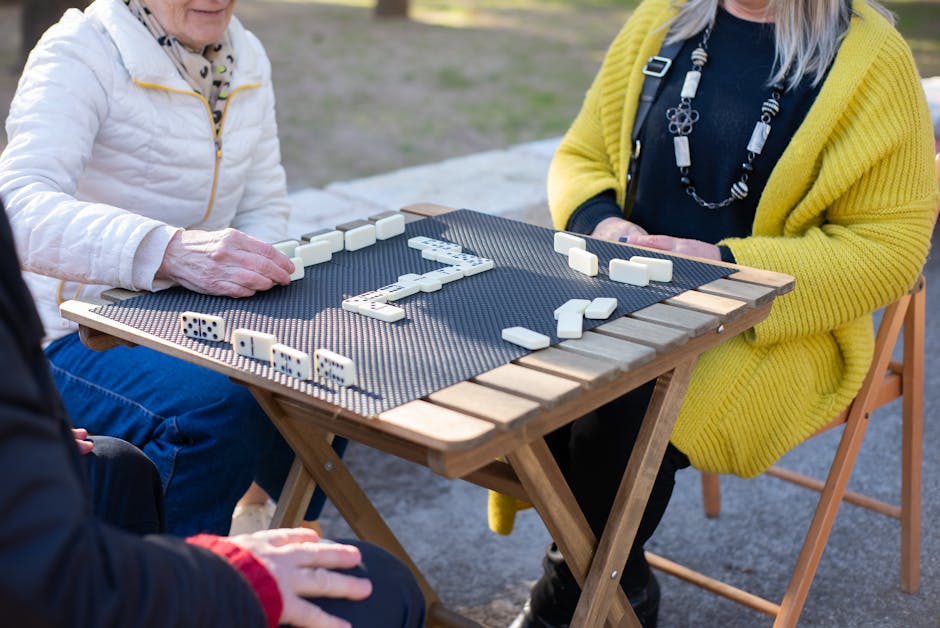 Idosos a jogar dominó numa mesa ao ar livre, a desfrutar do tempo livre.