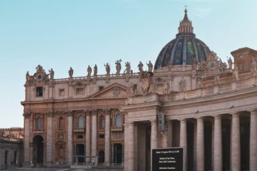 Captura da icónica cúpula e fachada da Basílica de São Pedro na Cidade do Vaticano, exibindo arquitetura barroca.