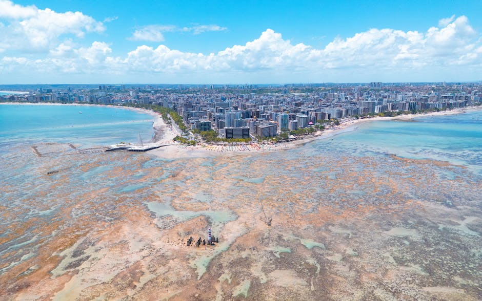 Vista aérea deslumbrante de Maceió, Brasil, mostrando a costa vibrante, a paisagem urbana e as águas azul-turquesa.