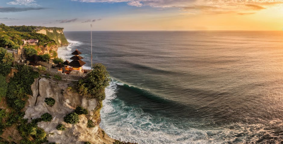 Uma vista aérea deslumbrante do Templo de Uluwatu empoleirado em falésias com vista para o oceano ao pôr do sol em Bali, Indonésia.