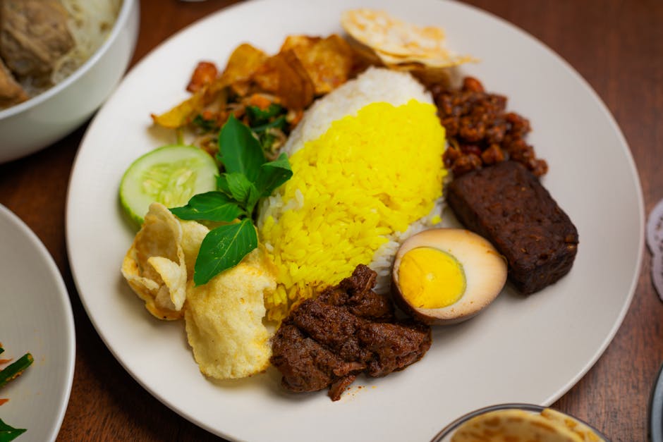 Prato colorido de Nasi Campur tradicional indonésio com arroz amarelo, bife grelhado, ovo e sambal.