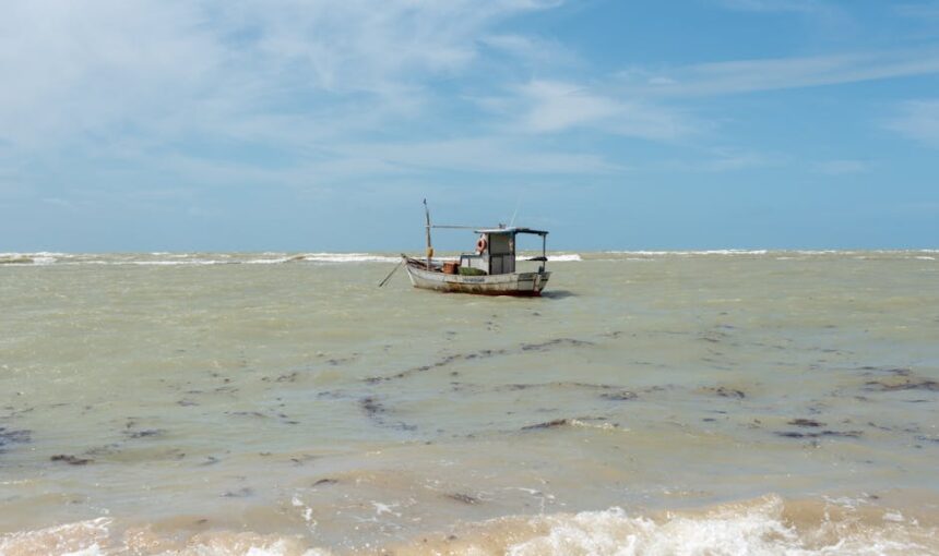 Um barco de pesca solitário flutua pacificamente no oceano perto de Arraial d'Ajuda, Bahia, Brasil.