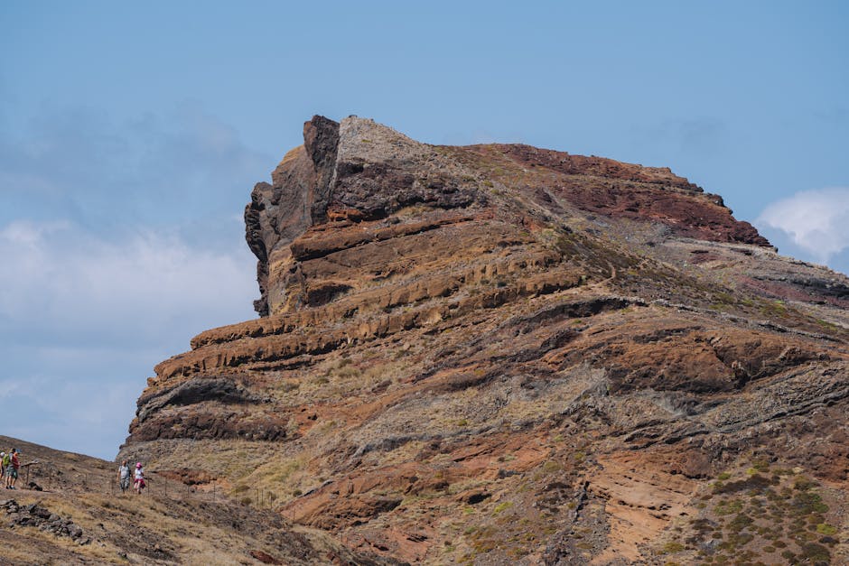 Explore uma paisagem deslumbrante de montanhas rochosas com caminhantes em Cabo Verde, sob um céu azul brilhante.