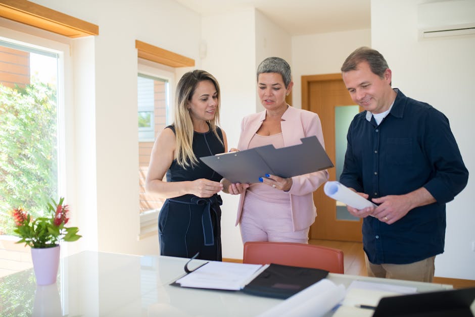 Três profissionais imobiliários a analisar documentos num escritório moderno, focados na venda de uma propriedade.
