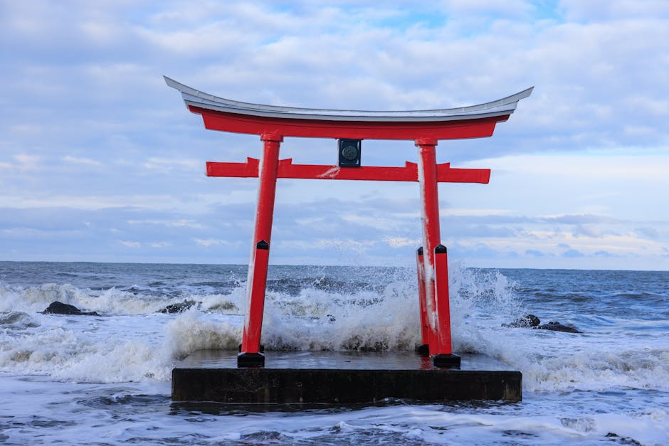 Um deslumbrante portão torii vermelho ergue-se em meio a ondas que rebentam em Shosambetsu, Japão.
