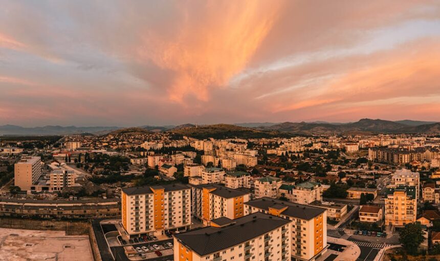 Vista aérea panorâmica de Podgorica, Montenegro ao pôr do sol, com céus vibrantes e arquitetura urbana.