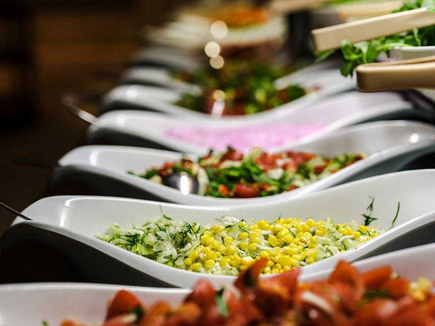 Uma seleção vibrante de saladas servidas em elegantes pratos de cerâmica num buffet.