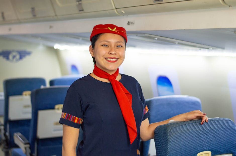 Assistente de bordo entusiasmada, com uniforme vermelho, sorri na cabine de um avião.