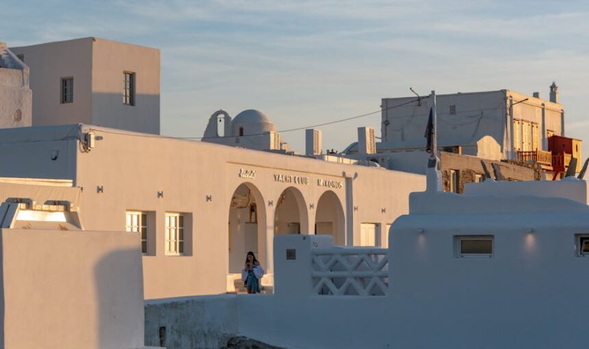 Edifícios brancos tradicionais em Mykonos ao pôr do sol, mostrando a beleza do Egeu.