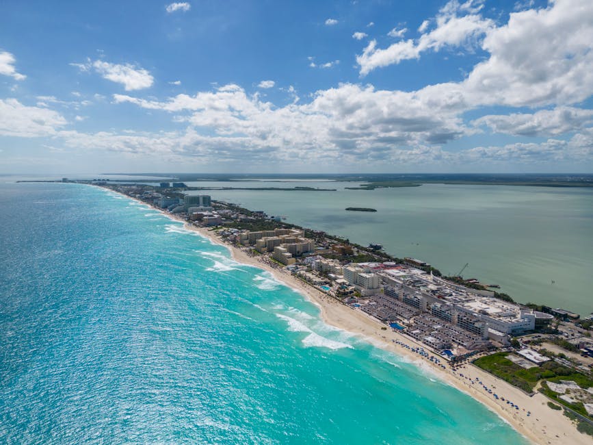 Vista aérea deslumbrante da costa de Cancún com águas azul-turquesa e hotéis da cidade sob um céu limpo.