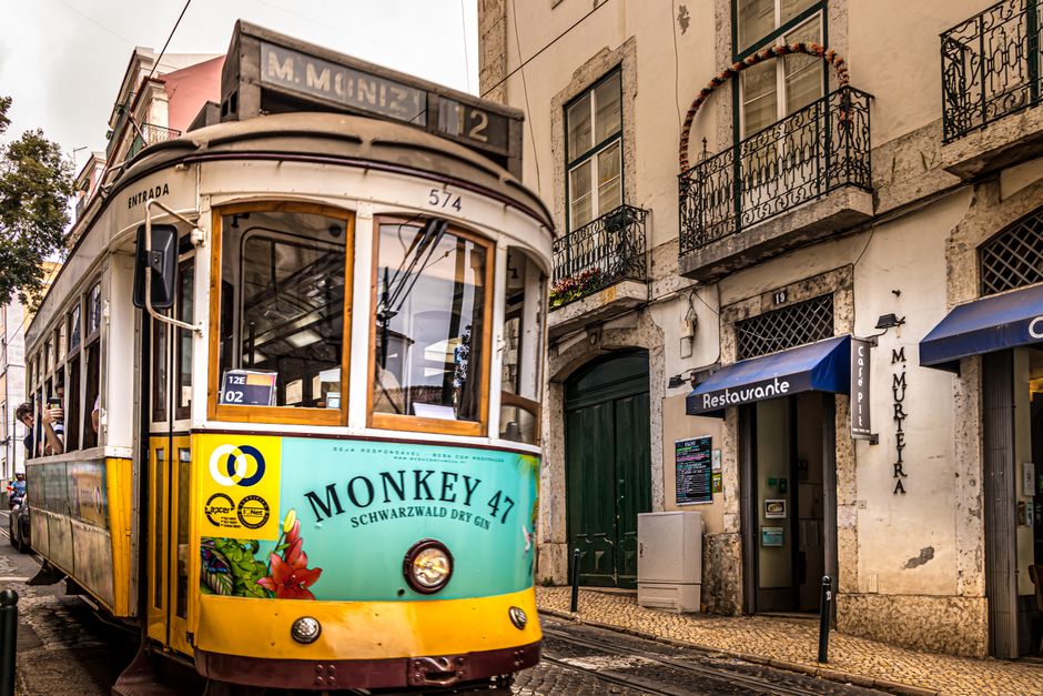 Um elétrico vibrante de Lisboa atravessa uma rua histórica, capturando a essência da vida urbana de Portugal.