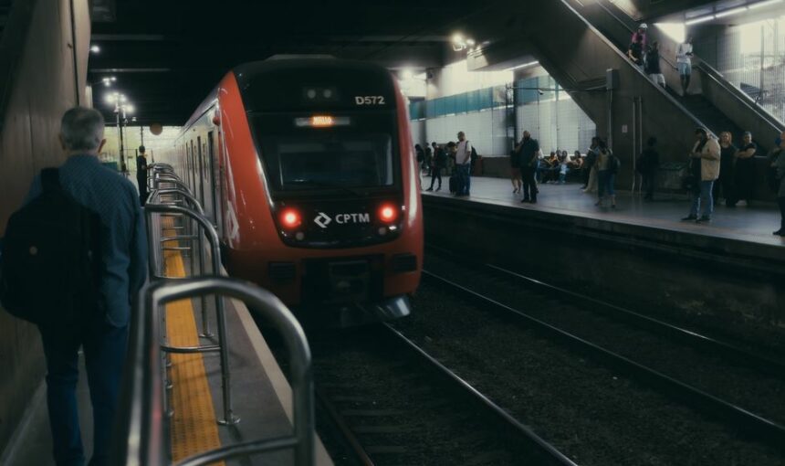 Um elegante comboio vermelho numa plataforma movimentada de estação ferroviária, à noite.