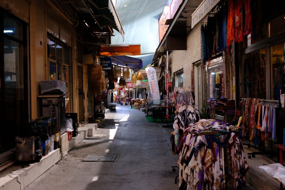 Explore a vibrante e estreita rua do mercado em Bornova, Izmir, com as suas lojas de têxteis e cultura local.