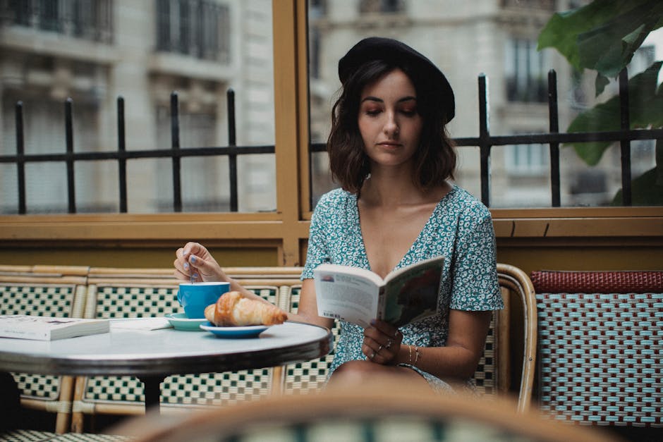 Uma mulher desfruta de um livro com café num café parisiense, exalando um ambiente calmo e clássico.