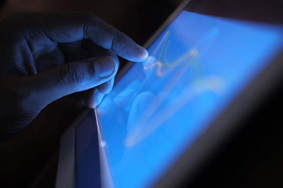 Close-up de uma mão a interagir com um tablet com ecrã tátil, a demonstrar o uso de tecnologia moderna.