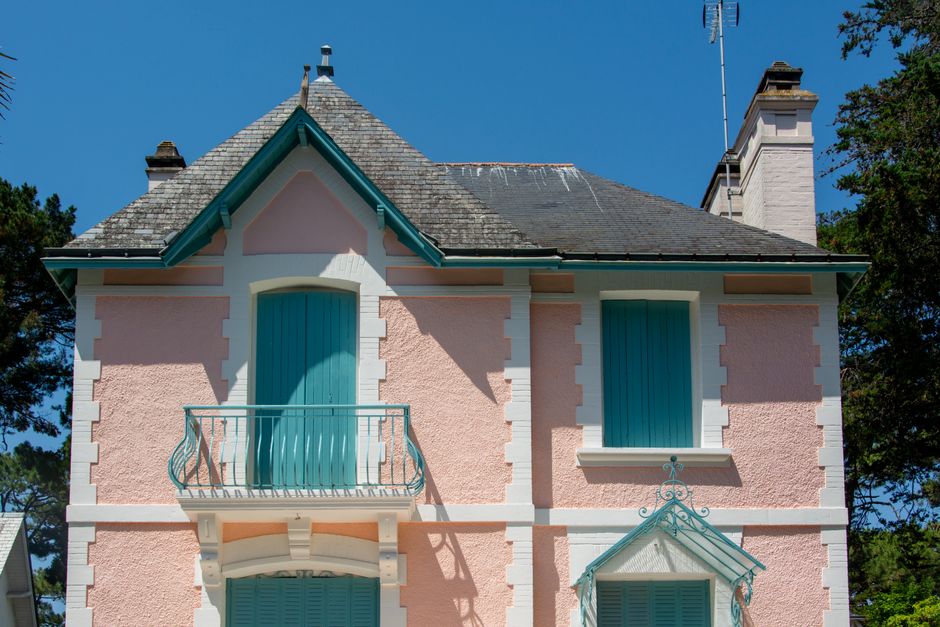 Casa pitoresca cor-de-rosa com detalhes em azul-petróleo sob um céu azul límpido em La Baule-Escoublac, França.