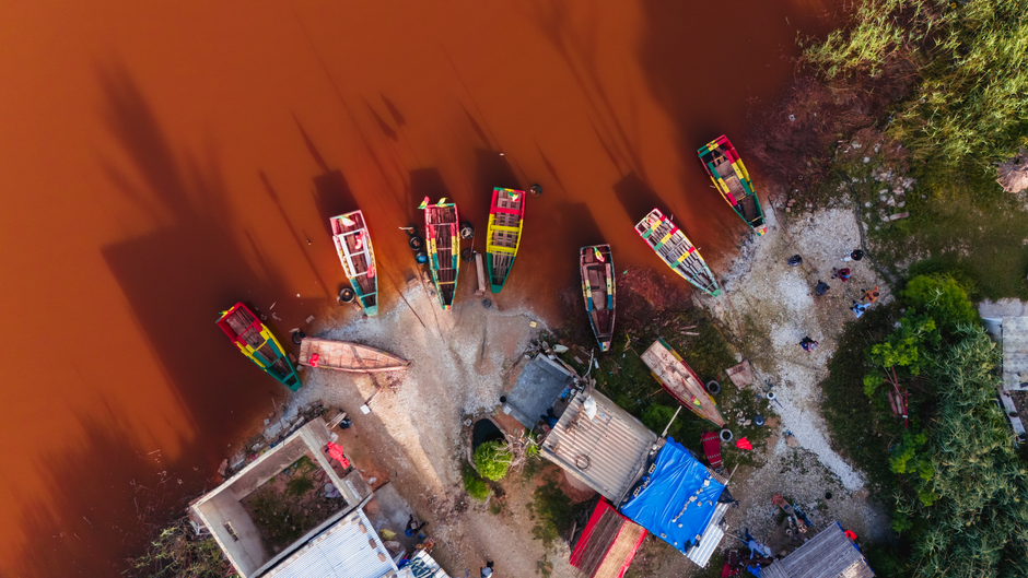 Captura de drone de barcos de pesca coloridos ancorados na margem do Lac Rose, Senegal.