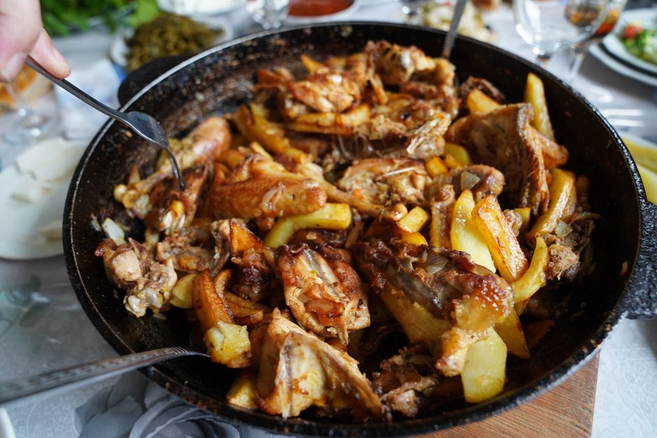 Delicioso prato de frango assado com batatas, servido numa frigideira grande, perfeito para reuniões de família.