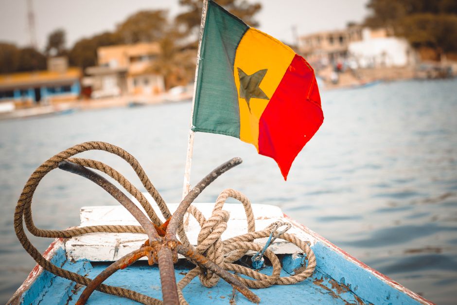 Bandeira senegalesa colorida e cordas náuticas no convés de um barco, perfeitos para temas de viagem.