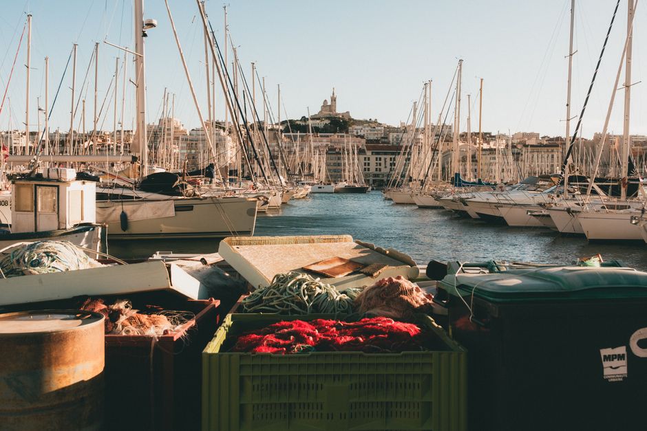 Uma cena vibrante do porto de Marselha com iates e a icónica Basílica de Notre-Dame de la Garde.