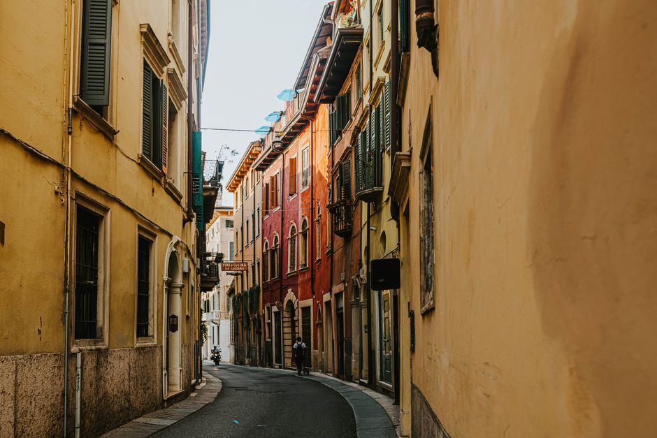 Explore uma rua estreita e pitoresca numa cidade antiga e histórica com fachadas de edifícios vibrantes.