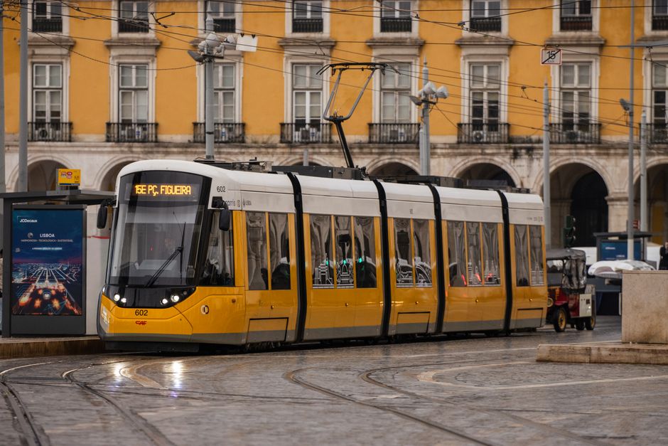 Um elétrico amarelo clássico a passar pelas ruas históricas de Lisboa, Portugal, exibindo a arquitetura portuguesa.