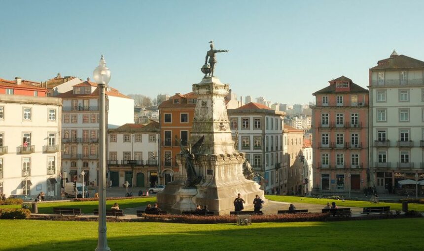 Bela vista de uma estátua numa praça histórica do Porto com arquitetura tradicional.
