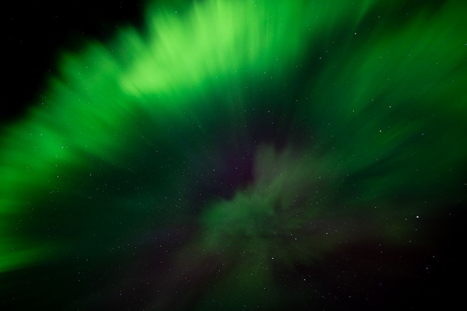Aurora boreal verde deslumbrante a iluminar o céu estrelado sobre a Islândia.