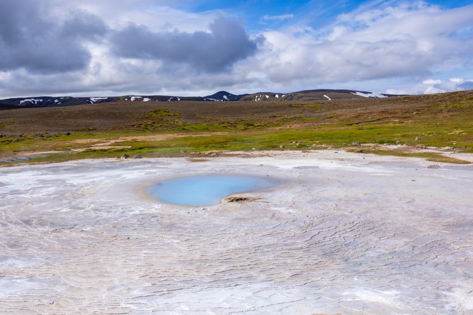 Magnífica área geotérmica islandesa com uma nascente termal azul contra um céu cénico.